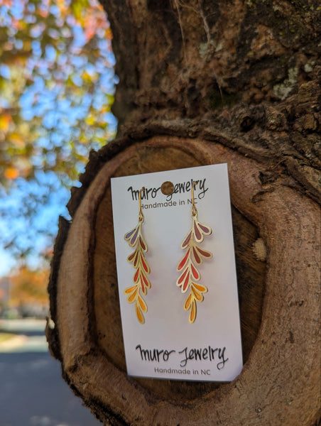 Muro Jewelry leaf-shaped earrings on a card against a natural background