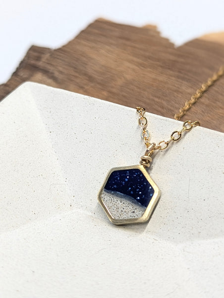 Hexagonal pendant necklace with blue and white gradient on a white surface