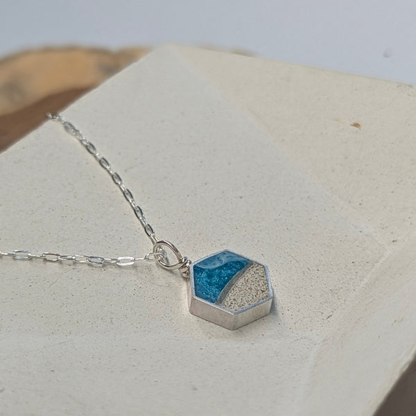 Necklace with a blue and silver geometric pendant on a light background