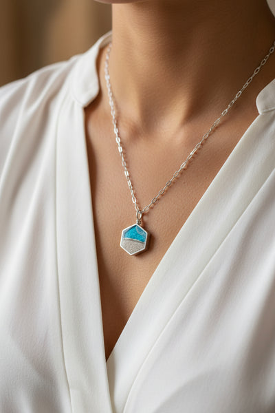 Hexagonal pendant necklace with blue and silver design on a light gray background