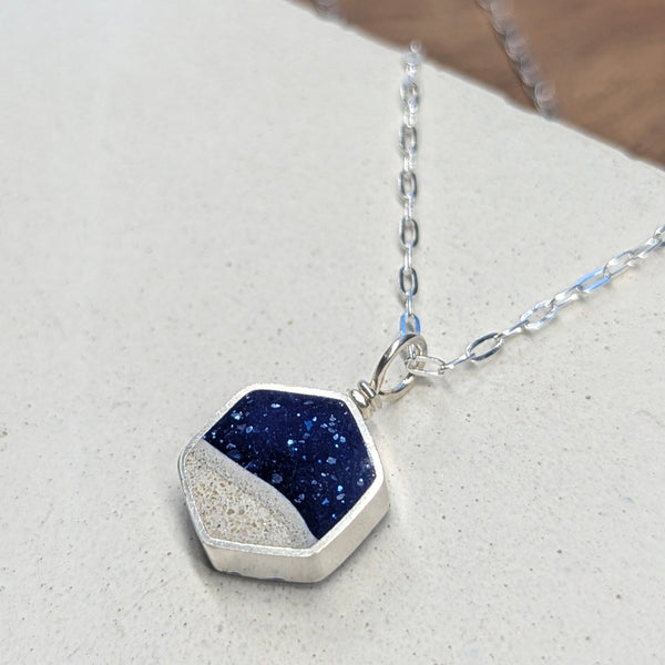 Necklace with a blue and silver pendant on a light gray surface