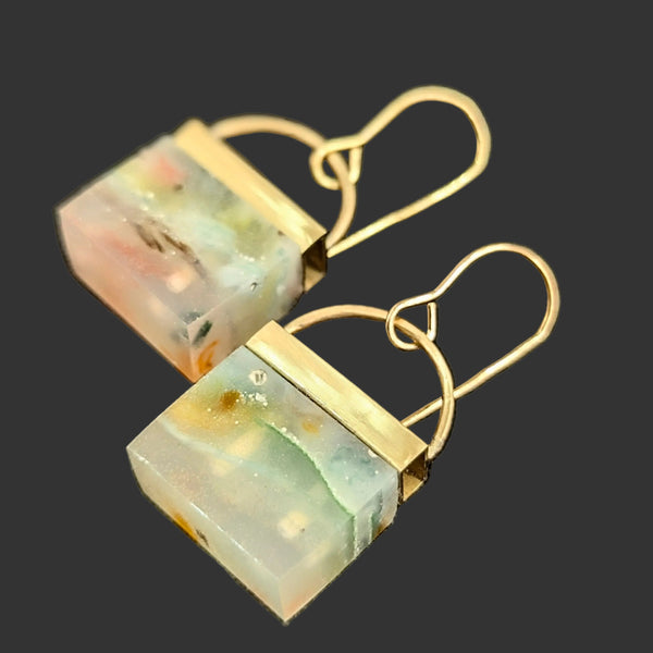 Pair of earrings with green and gold stone on a black background